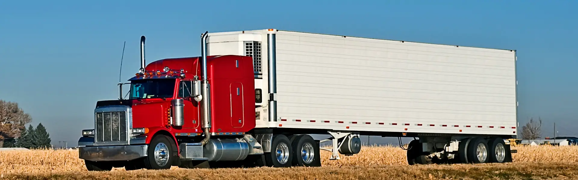 red semi truck with white trailer on road
