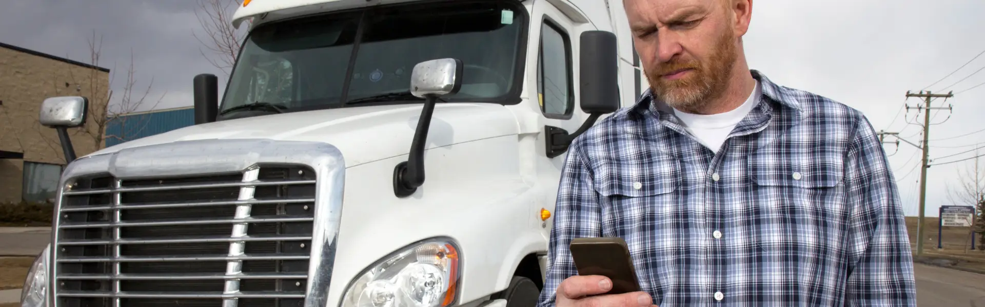 Man looking at phone with semi truck in background