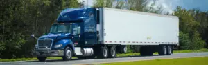 dark blue semi truck pulling white trailer