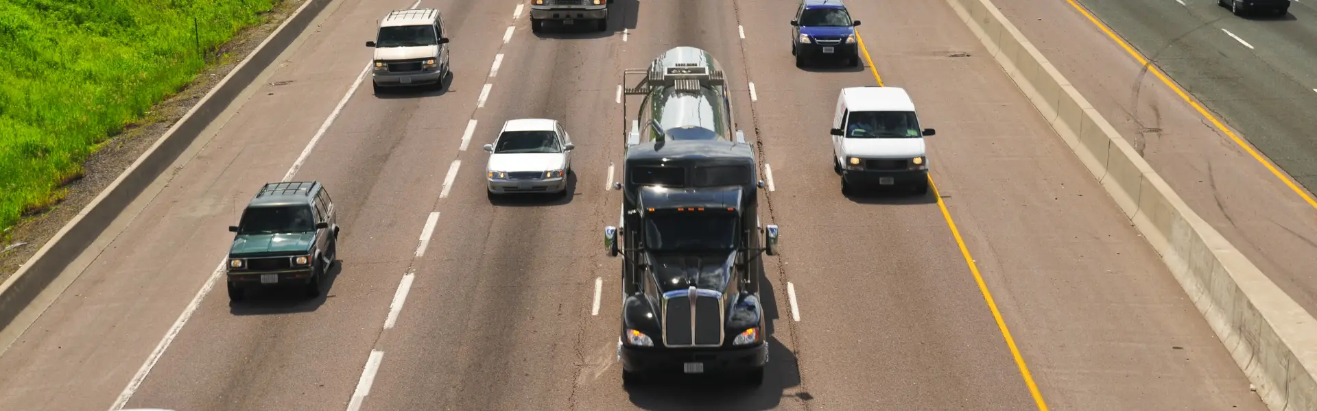 highway with cars and semi trucks in summer with green on sides of road