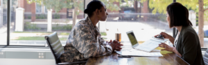 woman in military uniform talking with another woman with laptop