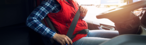 woman truck driver fastening seat belt in semi truck cab