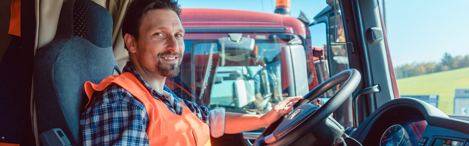 man in safety vest in cab of semi truck