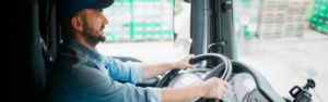 man sitting in cab of semi truck with hands on steering wheel