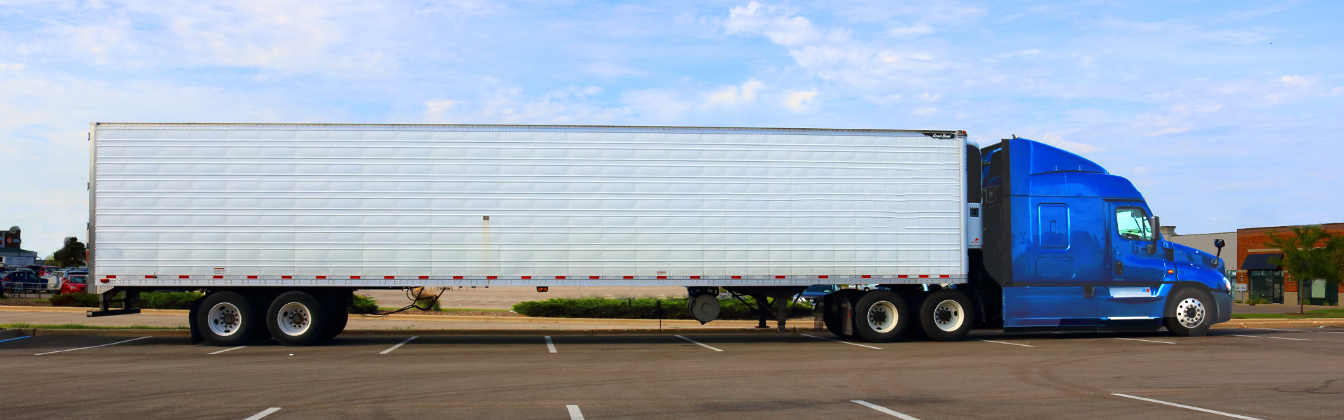 blue semi truck with white trailer in parking lot