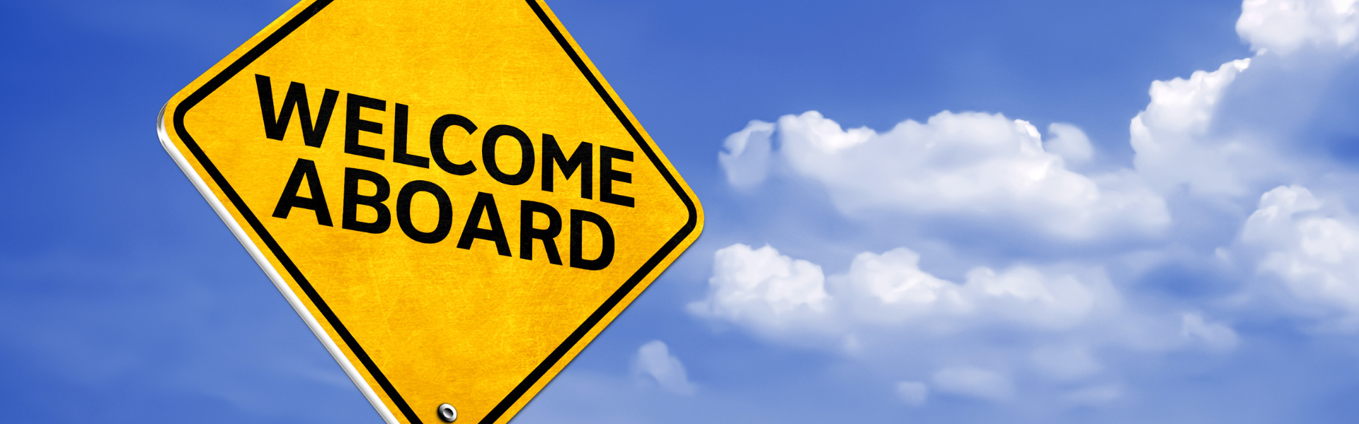 yellow welcome aboard road sign with a blue sky in the background