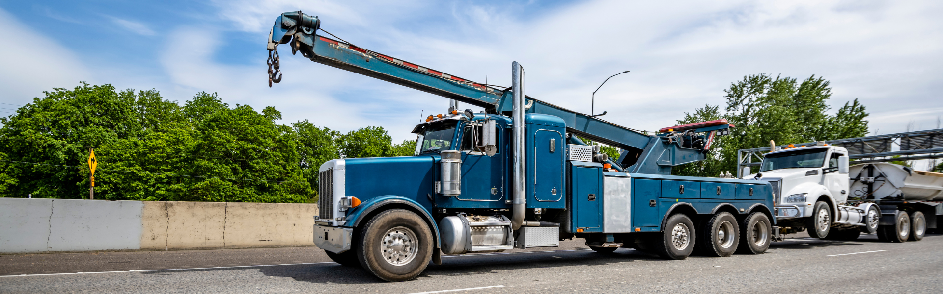 blue semi truck tow truck towing white semi truck