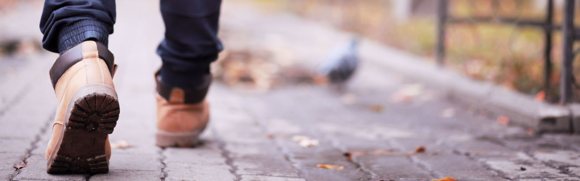 man in workboots walking on cobblestone path