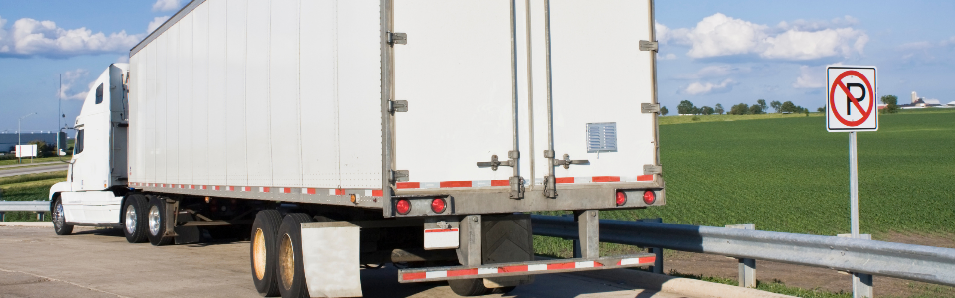 Semi truck parked on side of road next to no parking sign