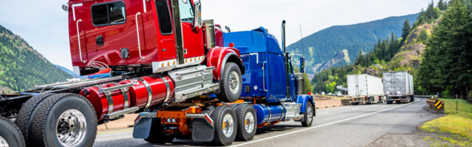 blue semi truck towing red semi truck