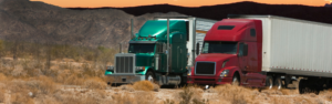 red and green semi trucks with white trailers and mountains in background