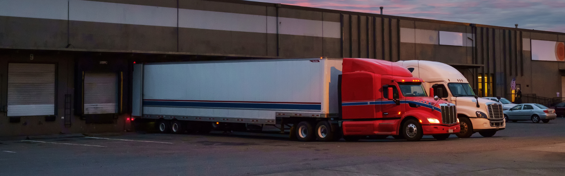 red and blue semi trucks backed up to commercial loading dock