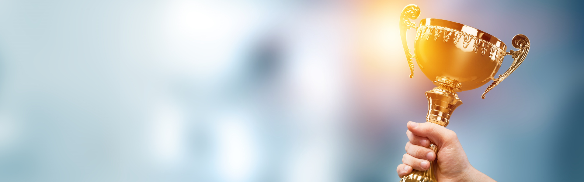 trophy in hand being held high on blurry background