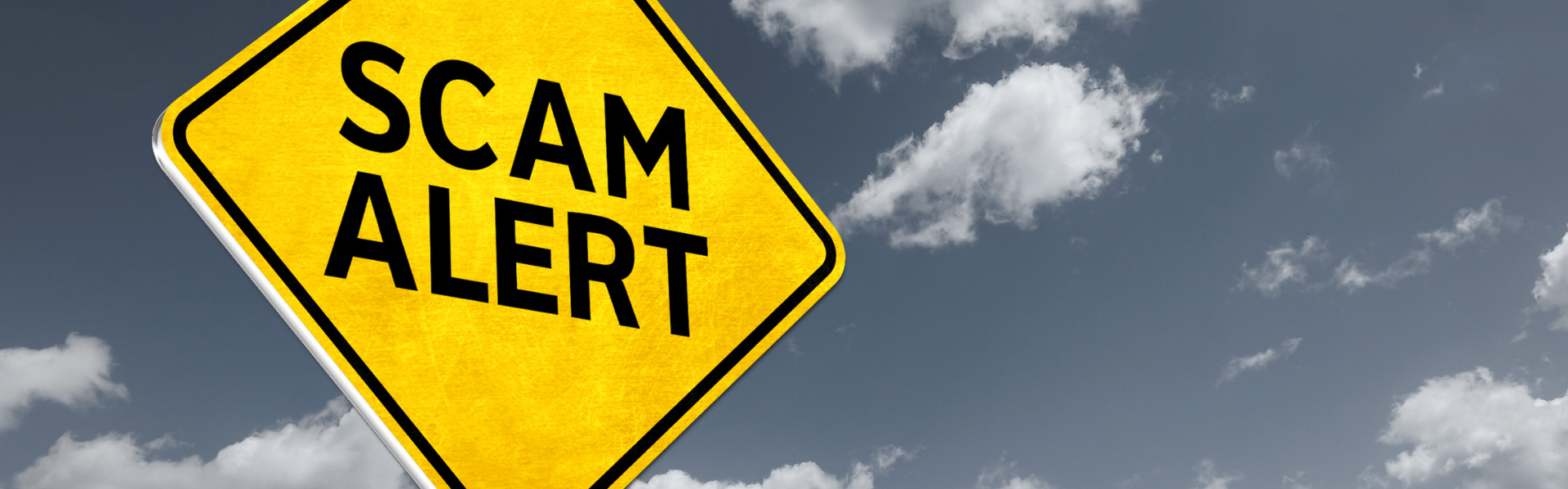 bright yellow scam alert sign on dark sky background