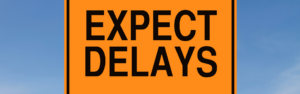 yellow sign with black lettering reading expect delays