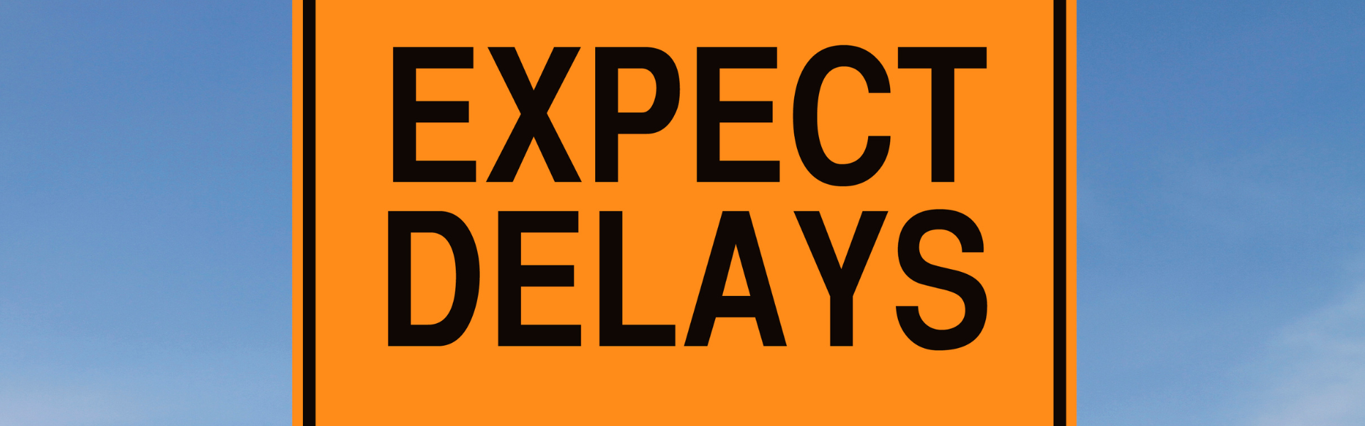 yellow sign with black lettering reading expect delays