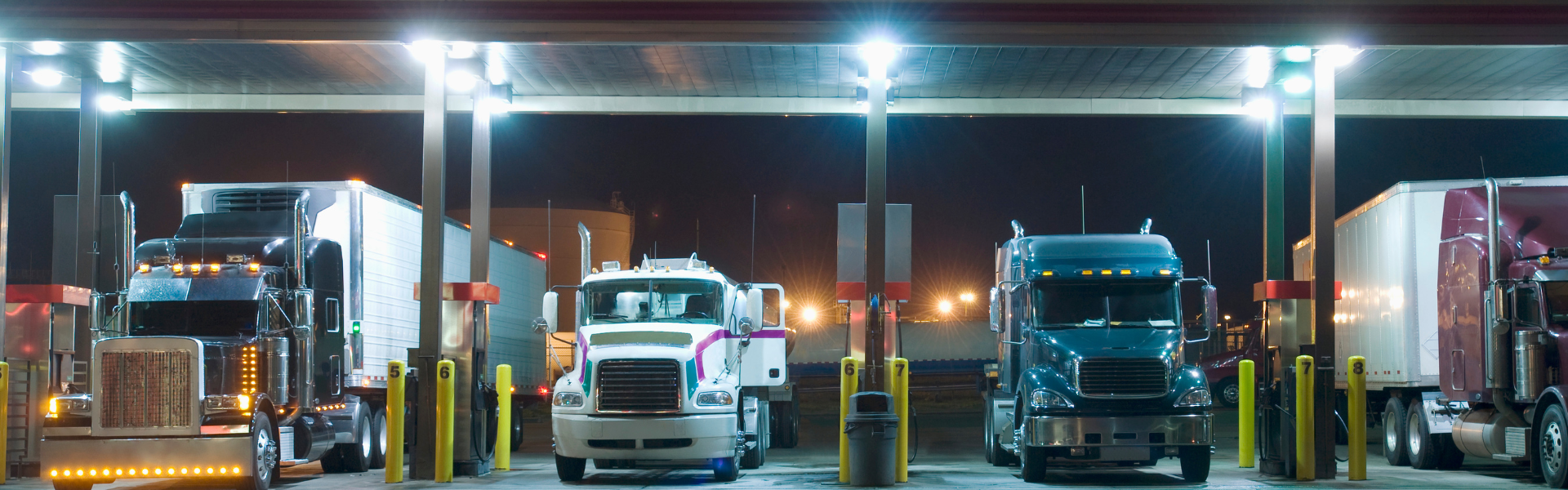 semi trucks parked under fuel island at truck stop