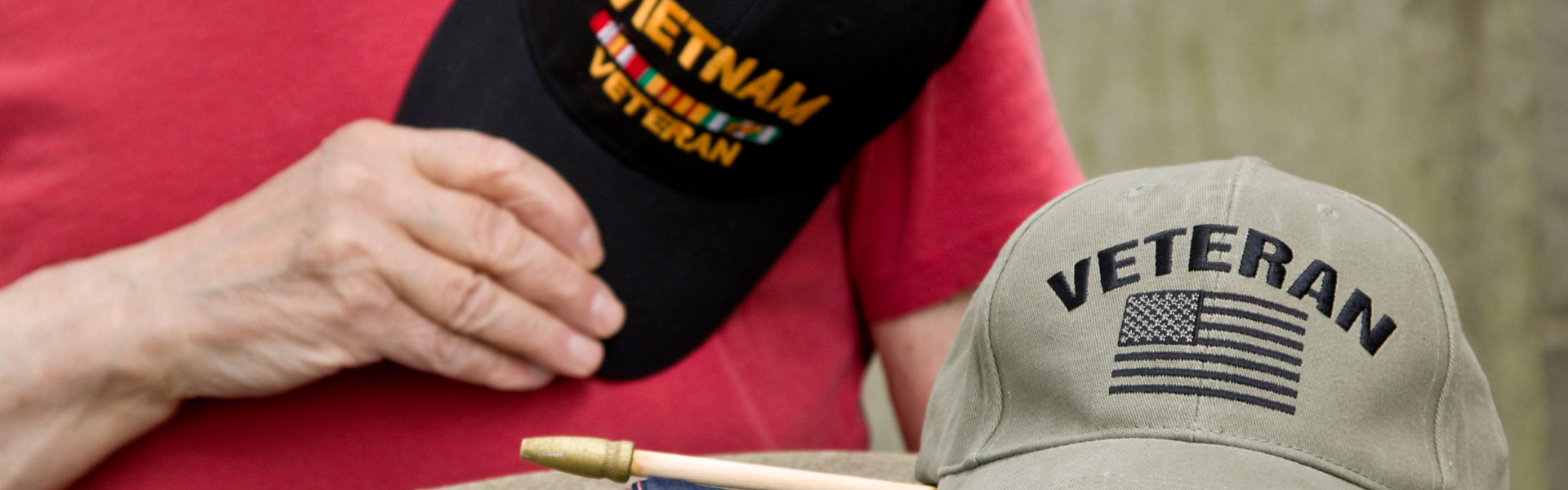 man holding veteran hat with another veteran hat in the foreground