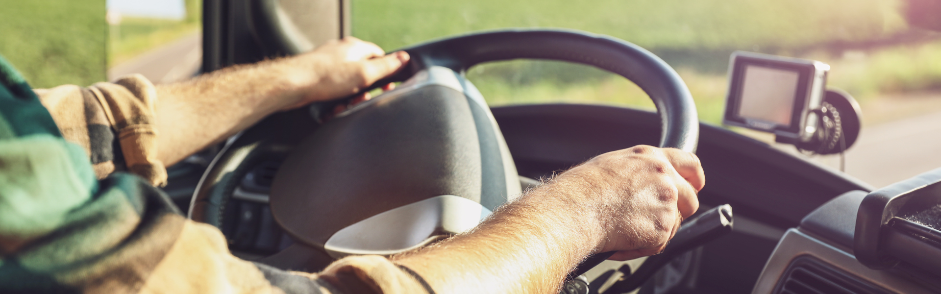 truck driver at the wheel of a semi truck view from inside the cab looking out through the windshield at the road