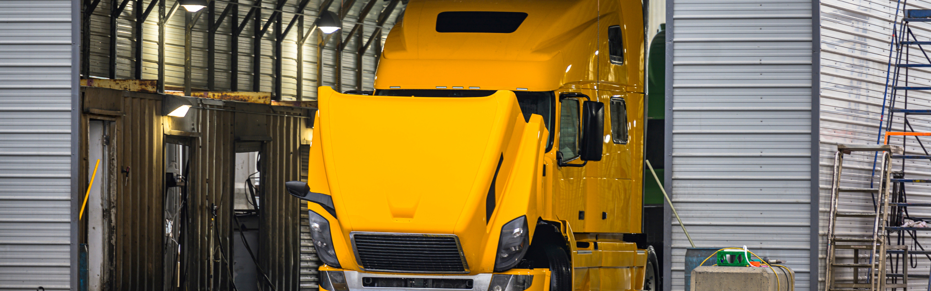 yellow semi truck in garage with hood up