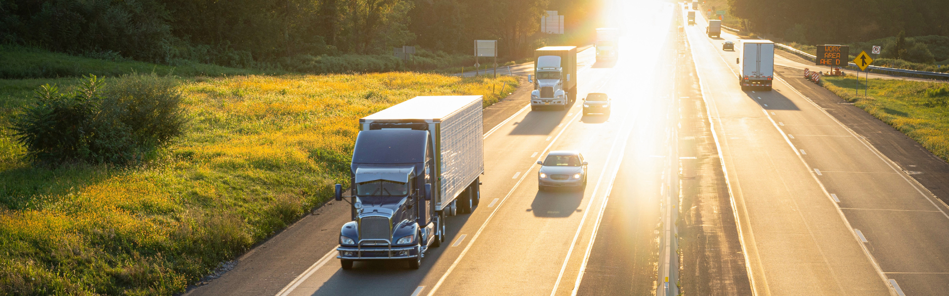 four lane highway with cars and semi trucks and bright sun