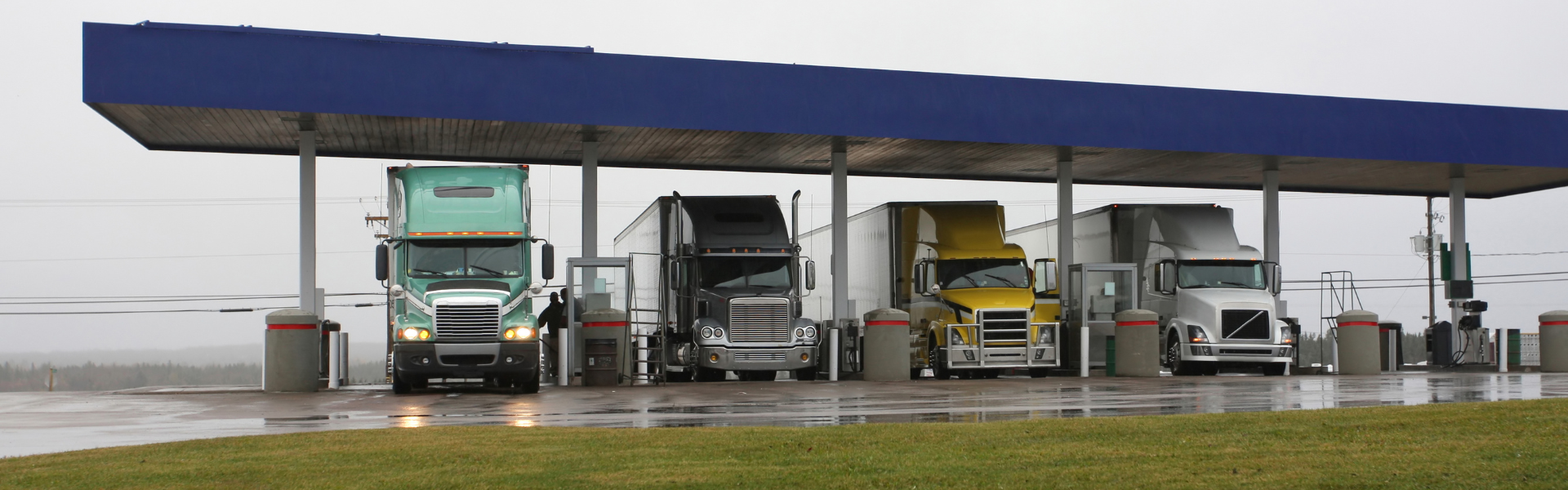 semi trucks parked under canopy at truck stop