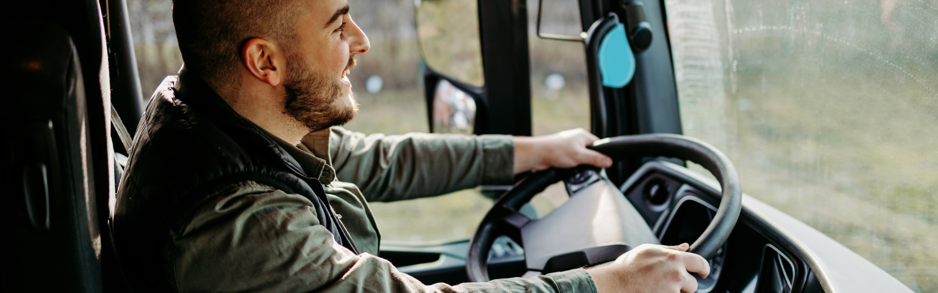 truck driver behind the wheel of semi truck in cab driving on road