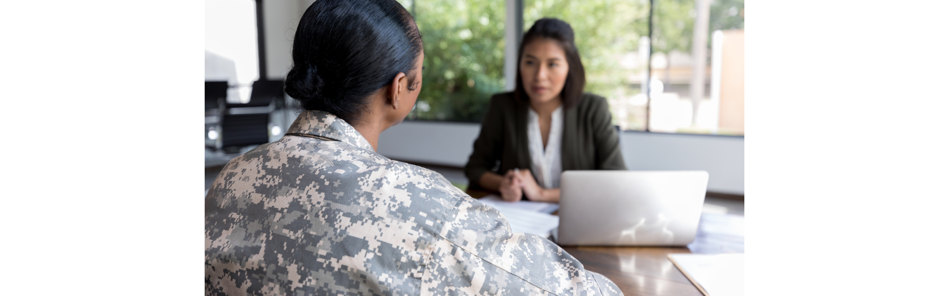 veteran woman in uniform sitting across from woman in suit with laptop