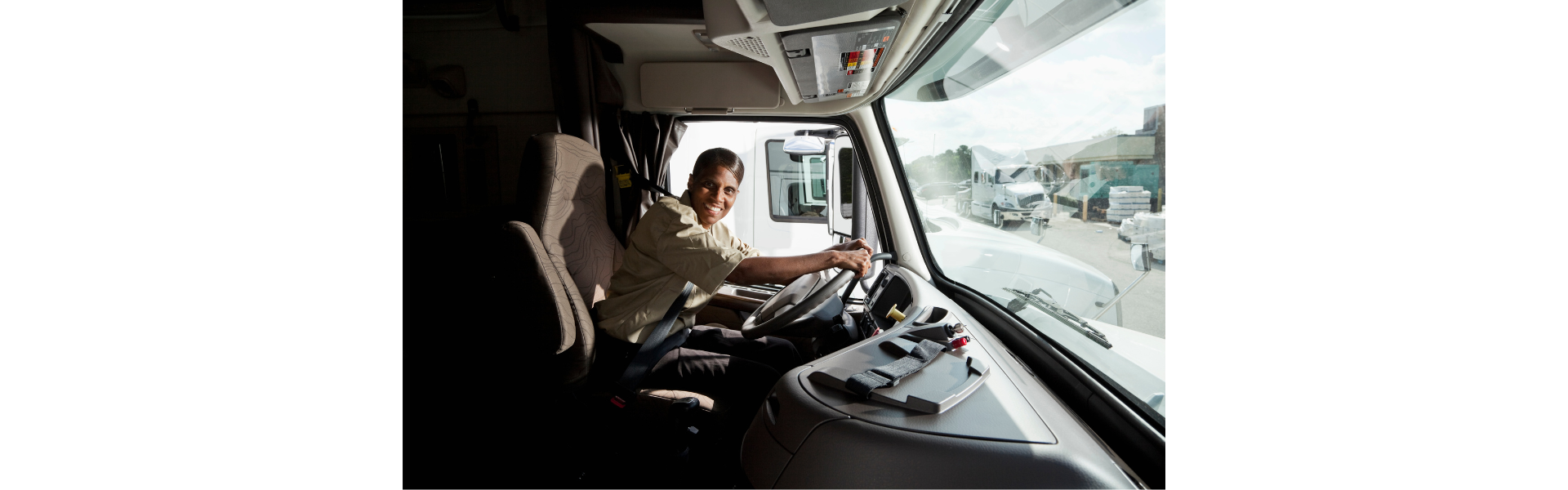 black woman at the wheel in the cab of a semi truck