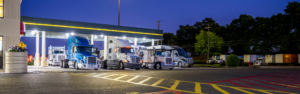 truck stop at night with semi trucks parked under the fuel island canopy