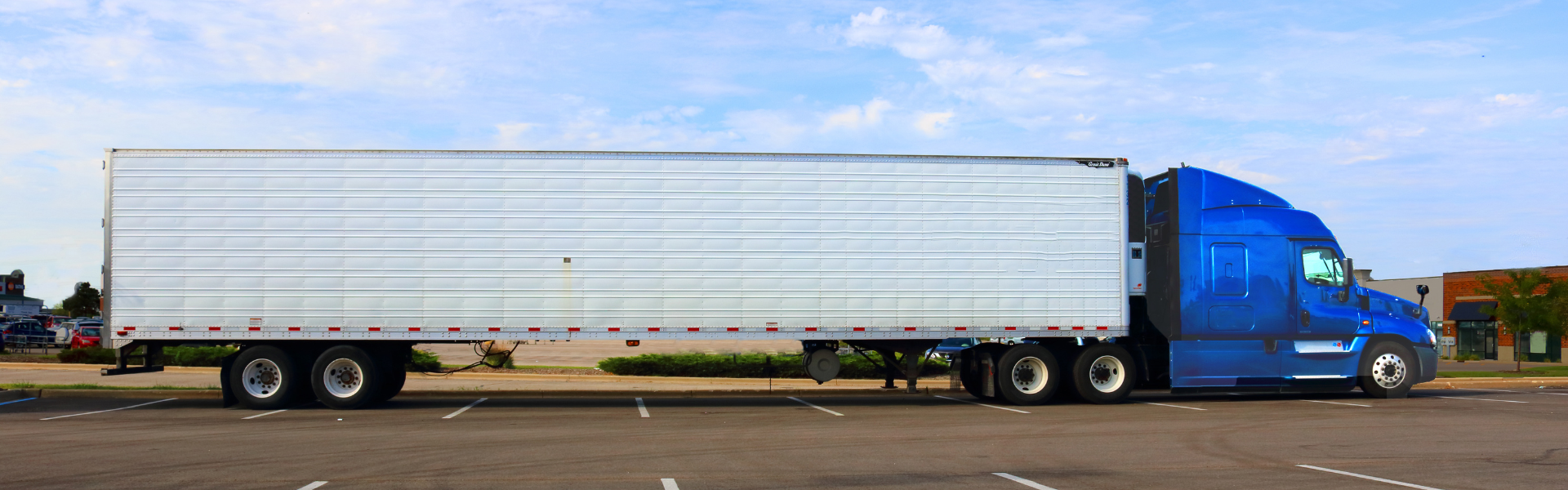 blue semi truck with white trailer parked in retail parking lot