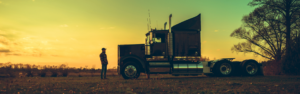 man standing next to semi truck silhoutted in sunset, veterans, cdl training