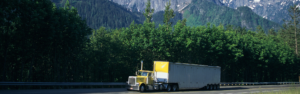 yellow semi truck navigating high elevation mountain road with forest and mountains in background, elevation and truck performance