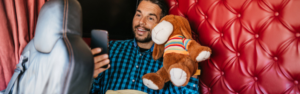 man with teddy bear holding phone in sleeper area of semi truck stopped at truck stop resting trucker trucker downtime