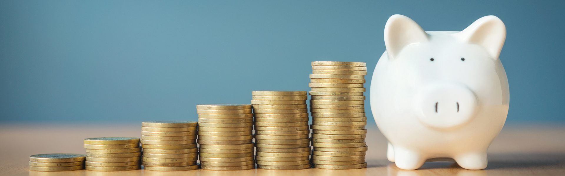 stacked coins next to piggy bank on blue background, U.S. Department of Transportation's PHMSA has proposed a rule to save businesses and consumers nearly $100 million annually by modernizing hazardous material transport regulations