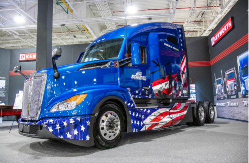 Image: a JR Shugel show truck turned to the left of the reader displaying a colorful truck wrap inspired by the American Flag.