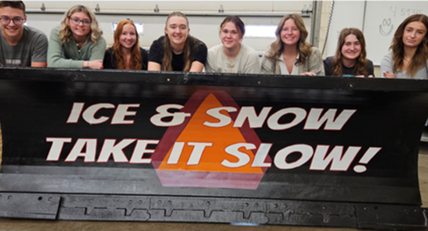 Wauseon High School students pose with their 2024 ODOT Paint-the Plow entry, "Ice & Snow, Take It Slow!"