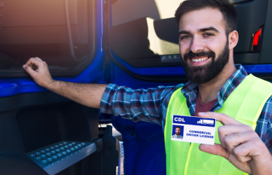 man standing next to blue semi truck holding CDL