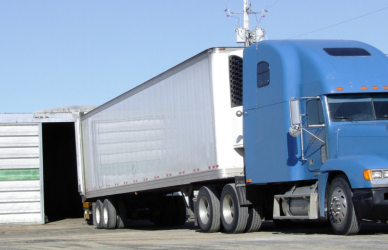 blue semi truck with white trailer ready to unload