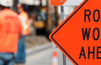 Road work ahead sign signaling I-57 expansion for truck drivers, including faster routes, reduced travel time, and improved efficiency.