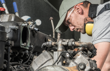 diesel technician leaned over diesel engine