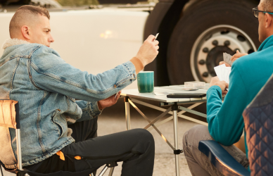 truckers sitting at folding table in truck stop parking lot