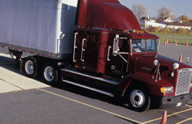 semi truck being guided by man into coned area