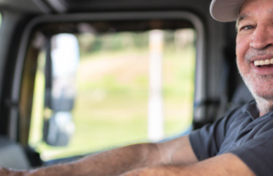 trucker smiling in cab of semi truck