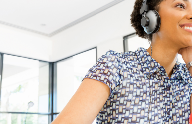 woman in office wearing headphones with coffee mug