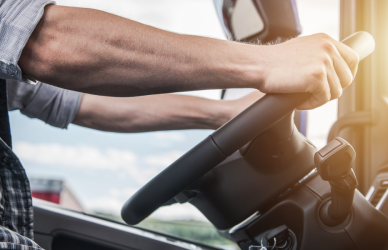 semi truck driver in the cab of a semi truck with sun coming in through windshield