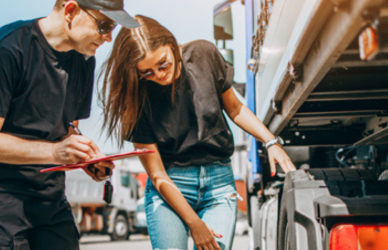 man and woman looking at semi truck with clipboard
