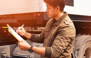 man with clip board looking at semi truck