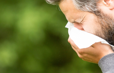 man sneezing into tissue