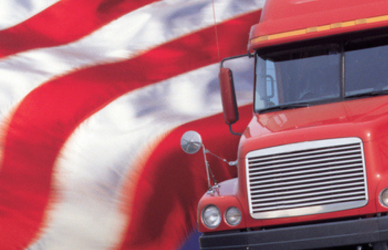 american flag waving behind red semi truck